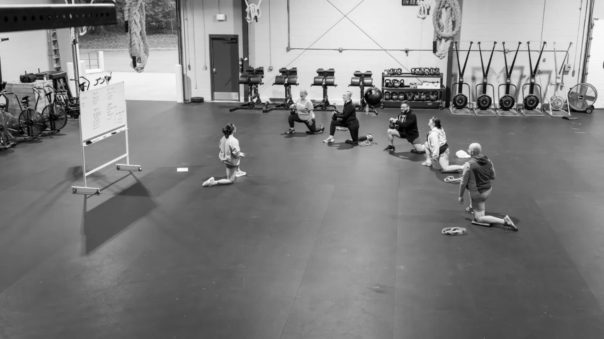 A group doing kneeling lunges on the gym floor